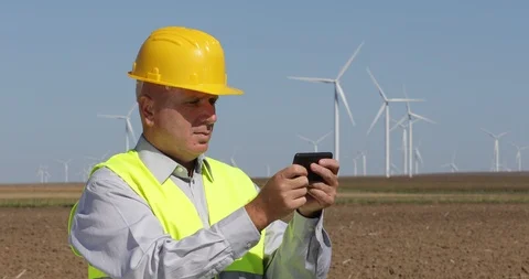 Engineer in a Field with Windmills Electricity Generators Text Using Cell Phone Video stock 102262020