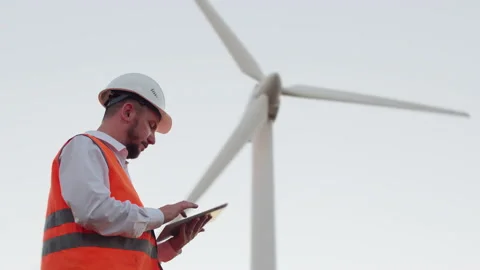 The engineer flips through a modern tablet, looks into the distance, then at the Stock Footage 136031881