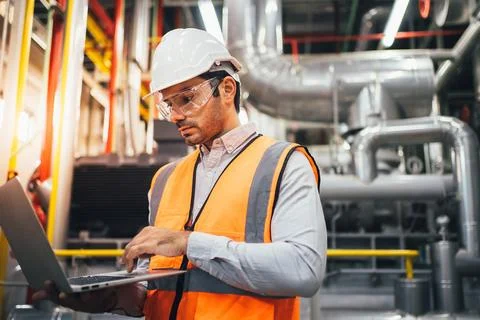 Engineer foreman using laptop controlling machine at industrial plant Stock Photos