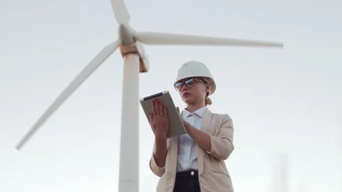 An engineer girl in a jacket and hard hat holds a digital tablet and looks into Stock Footage 135971088