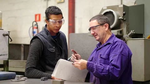 Engineer giving instructions at a worker in a cnc factory Stock Footage 258181850