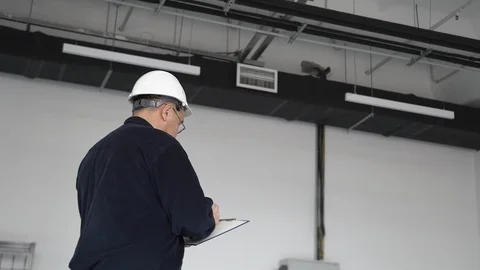 Engineer in glasses and a helmet writes information on work with a pen on paper Stock Footage 126576403