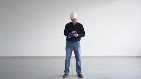 Engineer in glasses and a helmet writes information on work with a pen on paper Stock-Footage 126576582