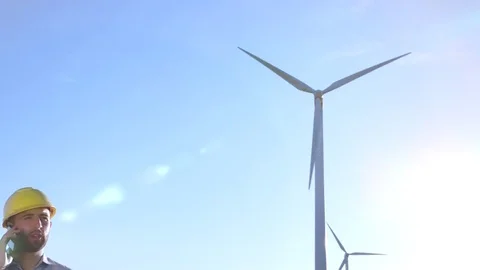 The engineer goes and talks on the phone against the background of windmills. Video stock 76555024