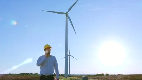 The engineer goes and talks on the phone against the background of windmills. Stock-Footage 76628037