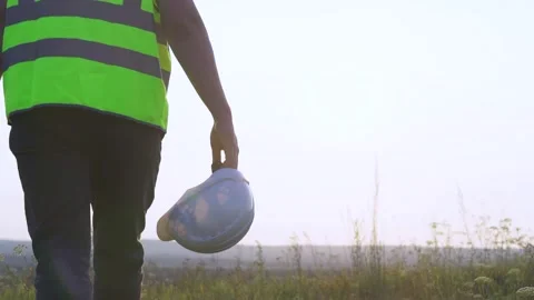The engineer goes to meet the sunset. Helmet in hand Stock Footage 252091184