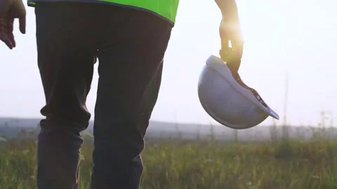 The engineer goes to meet the sunset. Helmet in hand Stock Footage 253324790