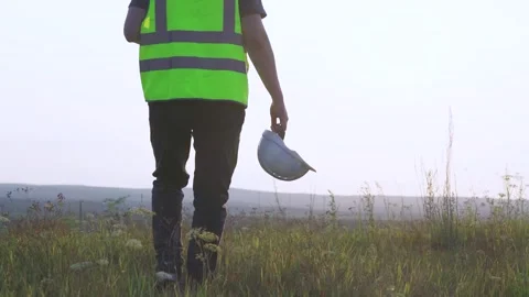 The engineer goes to meet the sunset. Helmet in hand Stock Footage 253431806
