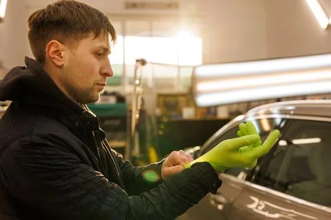 An engineer in green gloves fixing a car in a garage Stock Photos