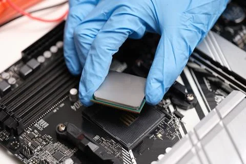 Engineer hand sets the processor to the motherboard Stock Photos
