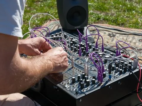 Engineer hands adjusting cables and knobs on a professional modular synthesizer Stock Photos