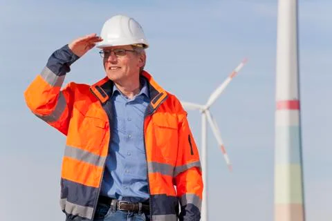 Engineer with hard hat and protective clothing in front of a windfarm 写真素材