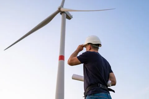 Engineer in hard hat holds a plan project for the construction of wind turbines Stock Photos