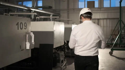 Engineer in hard hat is moving through a heavy industry factory with a tablet Stock Footage 114502836