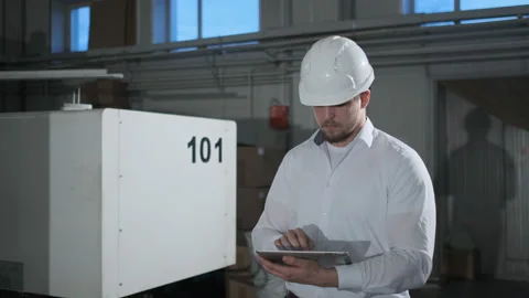 Engineer in hard hat is moving through a heavy industry factory with a tablet Stock Footage 114503460