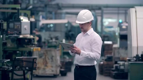 Engineer in hard hat is moving through a heavy industry factory with a tablet Stock Footage 171775447