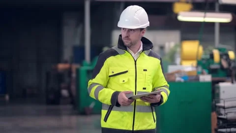 Engineer in hard hat is moving through a heavy industry factory with a tablet Stock Footage 171775496