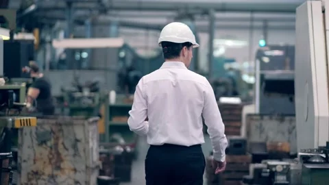 Engineer in hard hat is moving through a heavy industry factory with a tablet Stock Footage 172015606