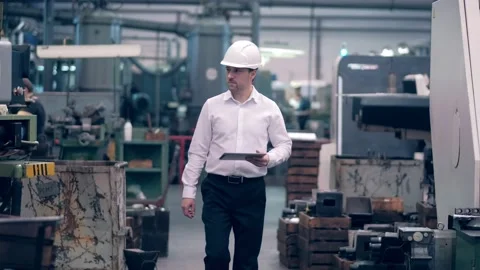Engineer in hard hat is moving through a heavy industry factory with a tablet Stock Footage 172015854