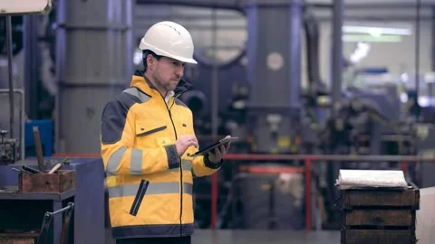 Engineer in hard hat is moving through a heavy industry factory with a tablet Stock Footage 172016253