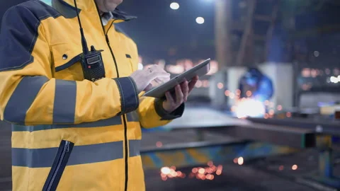 Engineer in hard hat is moving through a heavy industry factory with a tablet Stock Footage 240085737