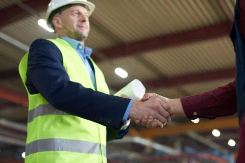 Engineer in hard hat shakes his colleagues hand. Stock Photos