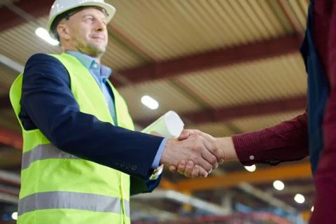 Engineer in hard hat shakes his colleagues hand. Stock Photos