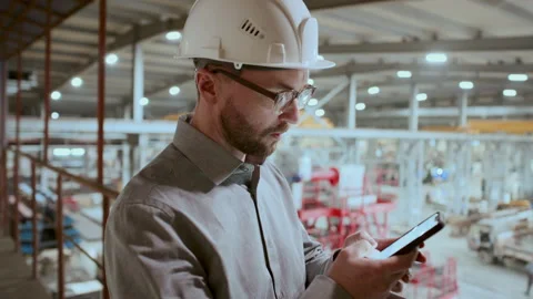 Engineer in Hard Hat Typing Message on Smartphone in Industrial Factory Stock Footage 296264741