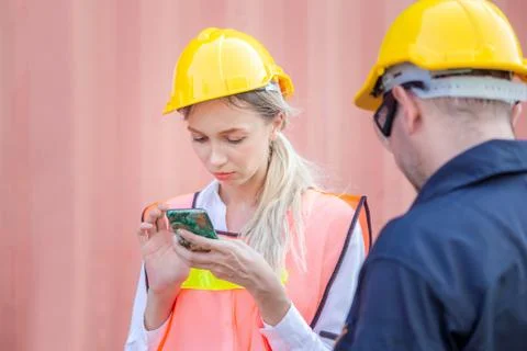 Engineer in the hard hat uses mobile phone, Industrial worker using smartphone 写真素材