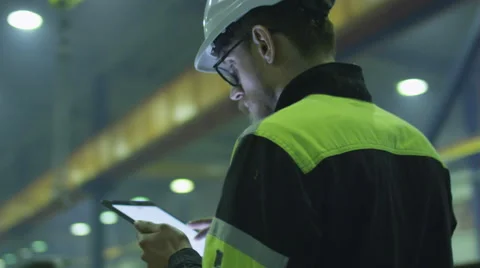 Engineer in hardhat is holding a tablet computer in a heavy industry factory Stock Footage