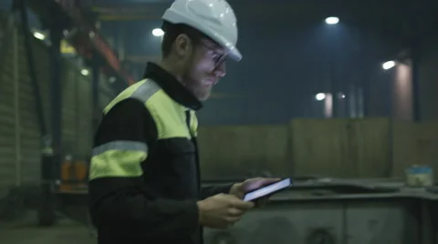 Engineer in hardhat is moving through a heavy industry factory with a tablet Vídeo Stock