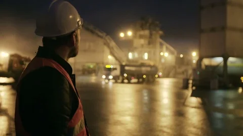 Engineer in hardhat with a tablet computer looks at truck on heavy industry Stock Footage