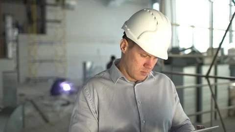 Engineer in hardhat is using a tablet computer in a heavy industry factory. slow Stock Footage 85899357