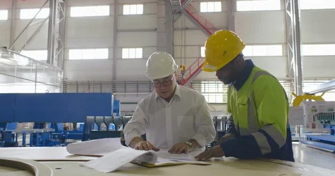 Engineer has conversation with maintenance engineer at factory. Developer in Stock Footage 118603892