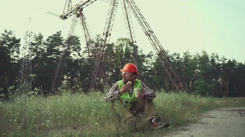 Engineer having lunch near power lines and electricity pylons in the field. An Stock Footage 157825858