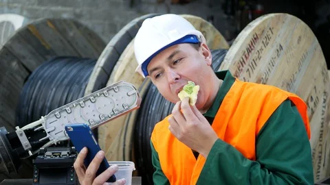 Engineer having lunch at workplace with a phone in his hands Stock Footage 128952042