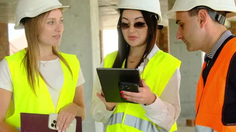 Engineer with headgear holds tablet standing near colleagues Video stock 317617564