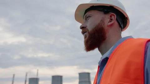 Engineer in a helmet on the background of the cooling towers of the power plant Stock Footage 201669582