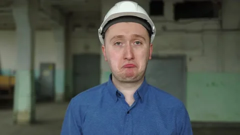 An engineer in a helmet looks at the camera, is very sad, upset, failure at work Stock Footage 152704390