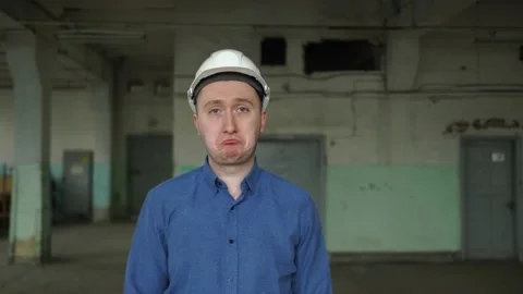 An engineer in a helmet looks at the camera, is very sad, upset, failure at work Stock Footage 152723439