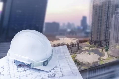Engineer helmet with plan for construction and blur city building background Stock Photos