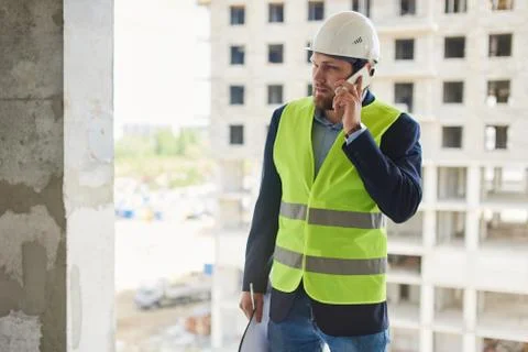 An engineer in a helmet talks on the phone. Stock Photos