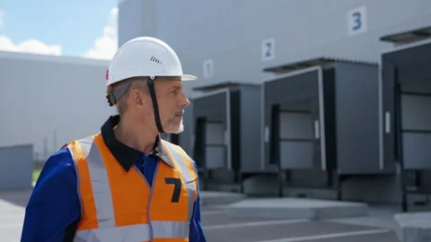 Engineer in helmet walks looking at large storage terminal Stock Footage 204775730
