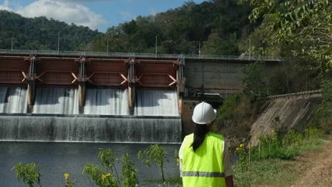 Engineer in helmet working outside against background of hydroelectric dam Stock Footage 229709594