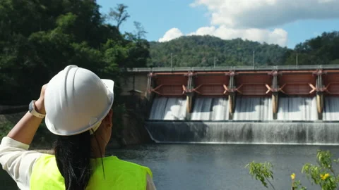 Engineer in helmet working outside against background of hydroelectric dam Stock Footage 229709763
