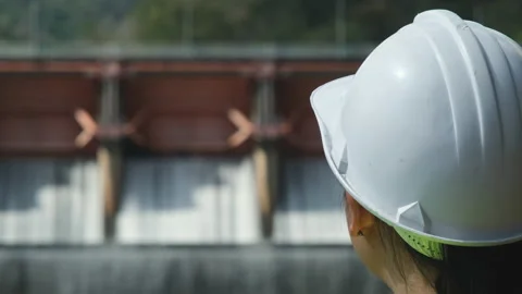 Engineer in helmet working outside against background of hydroelectric dam Stock Footage 229709931