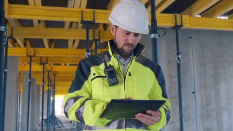 Engineer In Helmets With Tablet Device And Big Paper Drawings Discussing Video stock 113120728