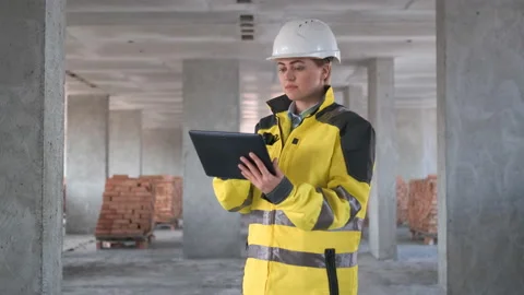 Engineer In Helmets With Tablet Device And Big Paper Drawings Discussing Video stock 114530173