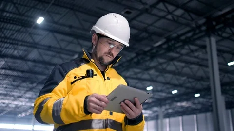 Engineer In Helmets With Tablet Device And Big Paper Drawings Discussing Stock Footage 128616646