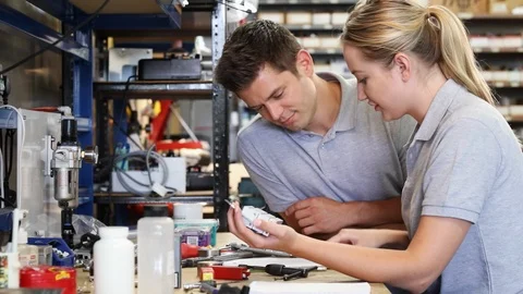 Engineer Helping Female Apprentice In Factory Video stock 93376507
